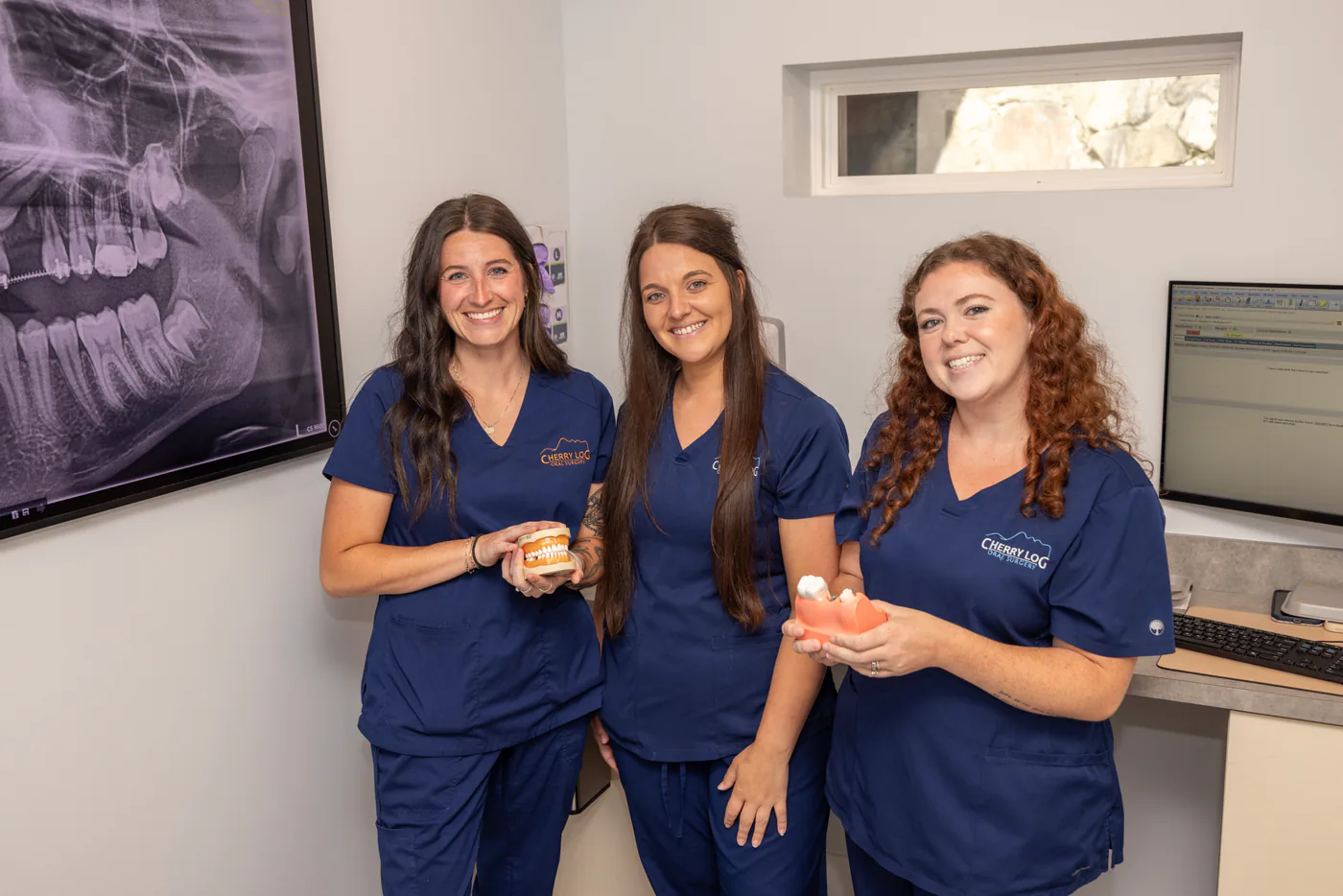 Cherry Log Oral Surgery team members holding dental implant models