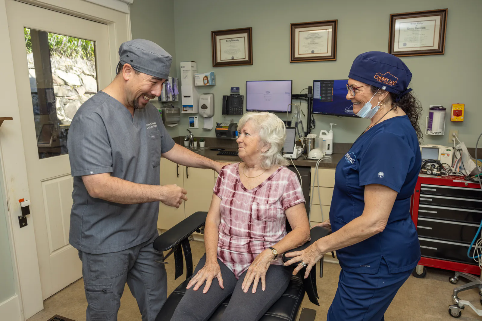 Dr. John Pritchett and a surgical assistant talking with a patient in the treatment room
