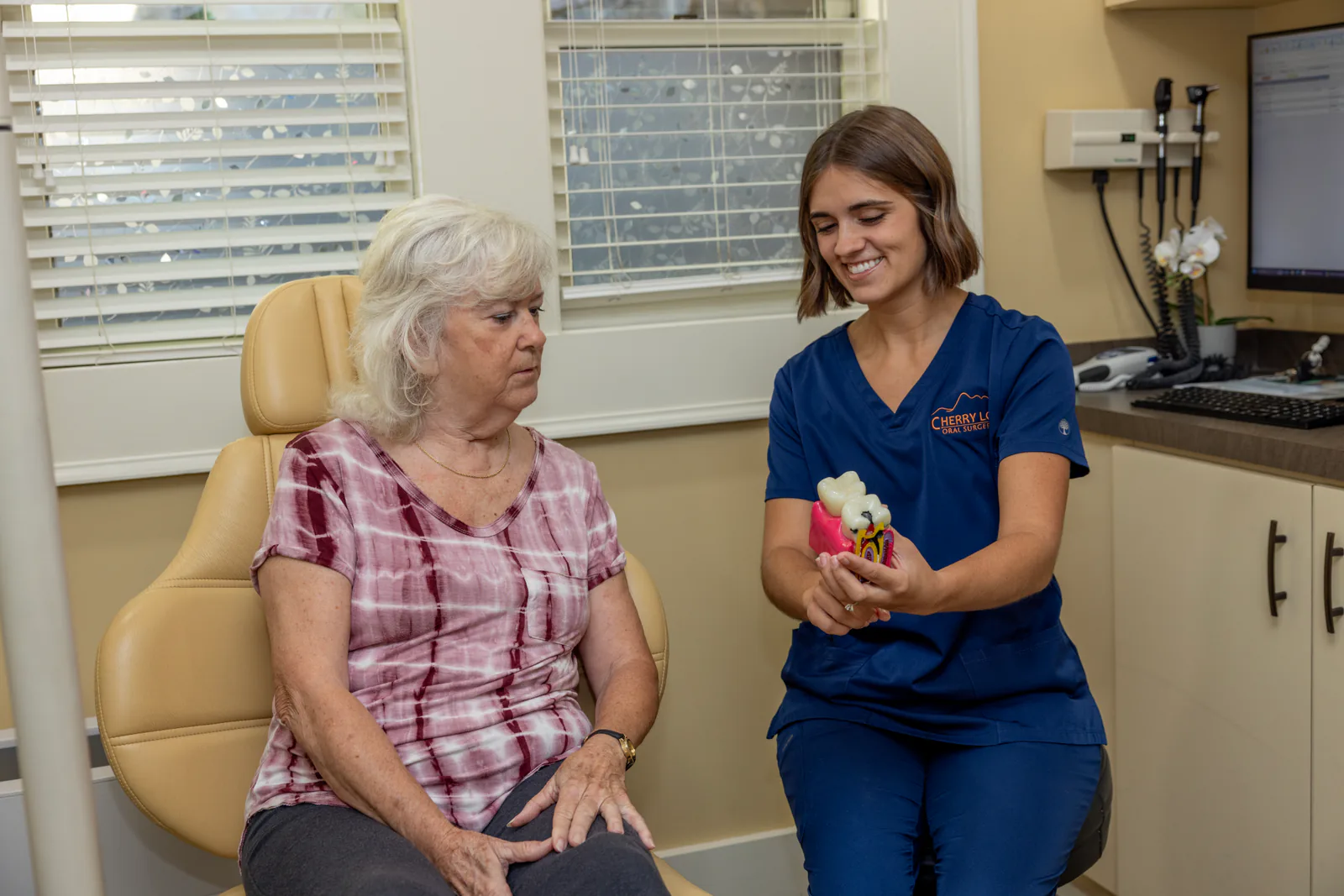 Team member using a dental model to explain implant treatment to a patient