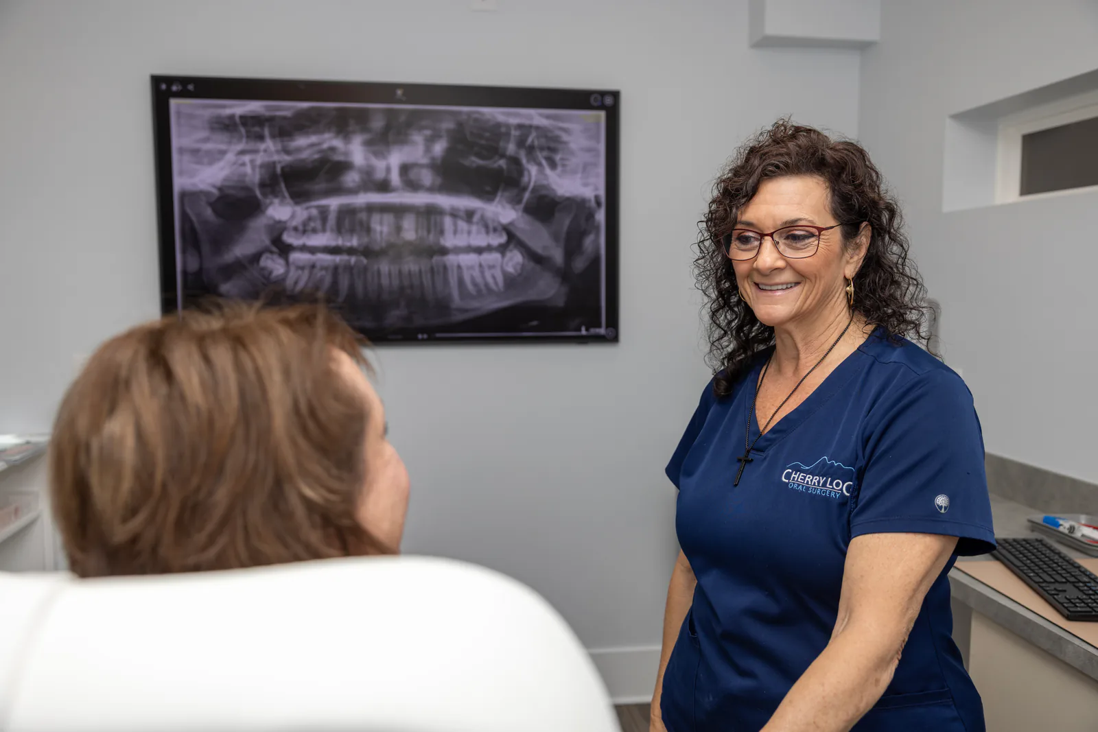 Cherry Log Oral Surgery team member reviewing a panoramic X-ray with a patient