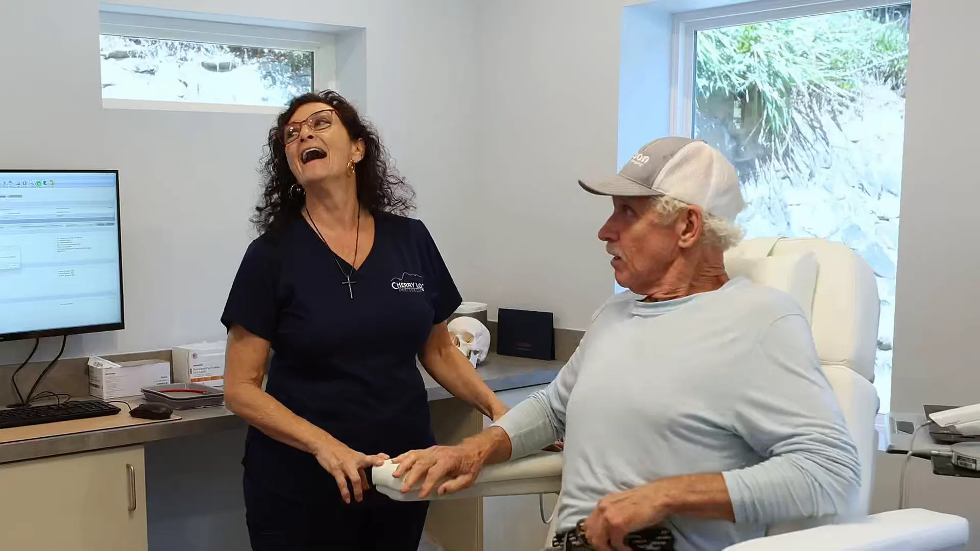 Cherry Log Oral Surgery team member laughing with a patient in a treatment room